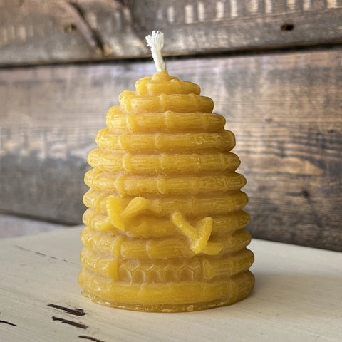 Yellow beehive-shaped candle on wooden surface