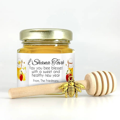Small jar of honey with personalized Shana Tovah label, gold bee charm, and wooden honey dipper on white background