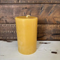 Yellow candle on a wooden surface with a rustic background