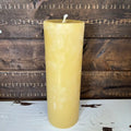 Yellow beeswax candle on a wooden surface with a rustic background