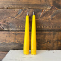 Two yellow candles on a wooden surface with a rustic background