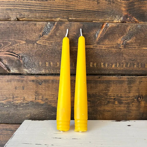 Two yellow candles on a wooden surface with a rustic background
