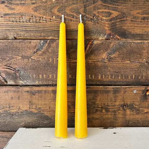 Two yellow candles on a wooden surface