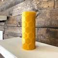 Yellow hexagonal candle on a white surface with a wooden background