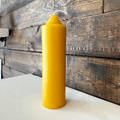 Yellow candle on a white surface with a wooden background