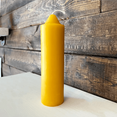 Yellow candle on a white surface with a wooden background
