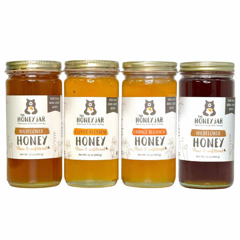 Four jars of honey with labels on a white background