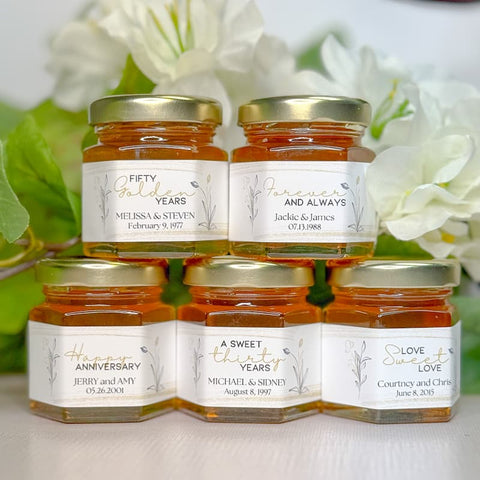 Five jars of honey with personalized labels on a white background with flowers.
