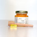 Honey jar with a personalized label and wooden honey dipper on a white background