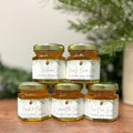 Jars of honey with personalized labels on a wooden surface with a blurred natural background