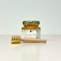 Jar of honey with a wooden honey dipper and thank you charm on a white background