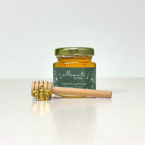 Jar of honey with a gold lid and wooden honey dipper on a white background