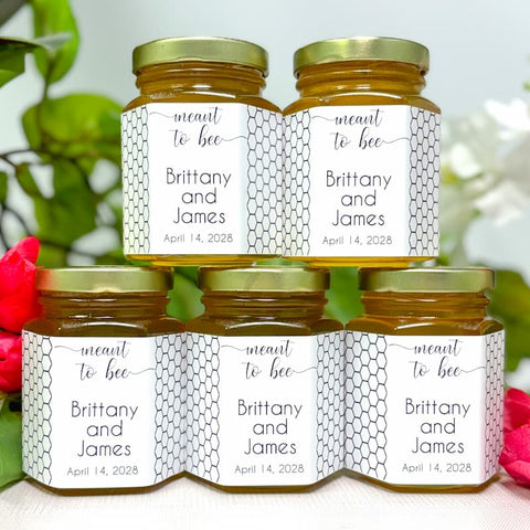 Five jars of honey with personalized labels on a white background with flowers.