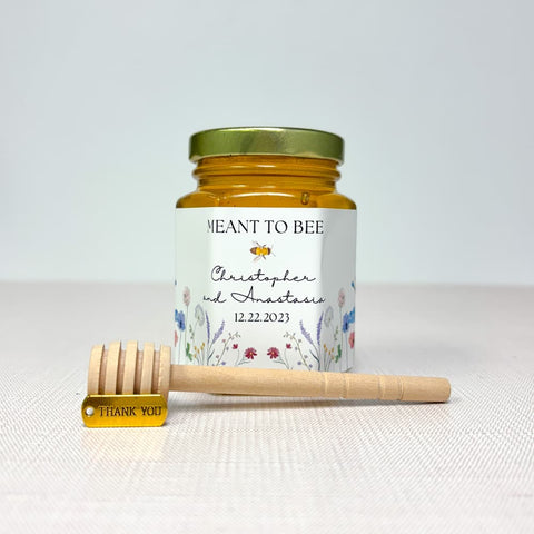 Honey jar with personalized label and wooden dipper on a white background