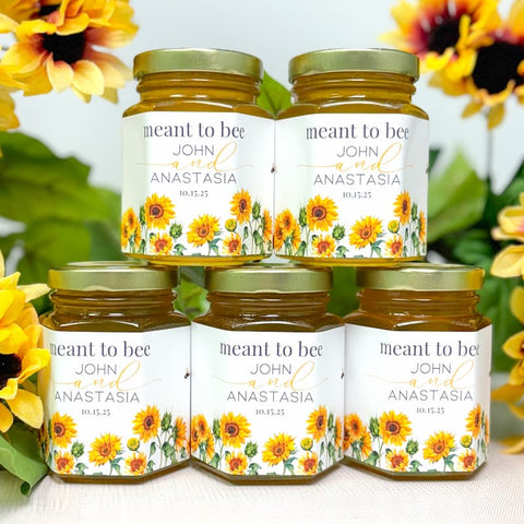 Honey jars with sunflower designs and personalized labels on a white surface with sunflowers in the background.