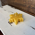 Beeswax candle shaped like a snowflake on a rustic wooden surface