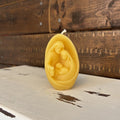Beeswax candle with a nativity scene design on a wooden surface