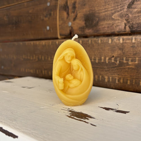 Beeswax candle with a nativity scene design on a wooden surface