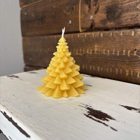 Yellow tree-shaped candle on a rustic wooden surface