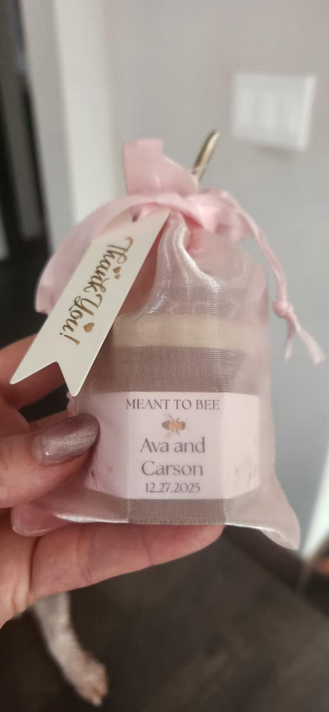 Hand holding a small bag with a personalized tag and a jar of honey inside