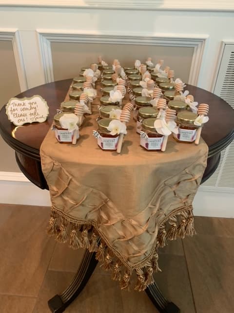 Table with small jars of honey and decorative items on a beige tablecloth