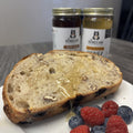 Toast with honey, berries, and jars of honey in the background.