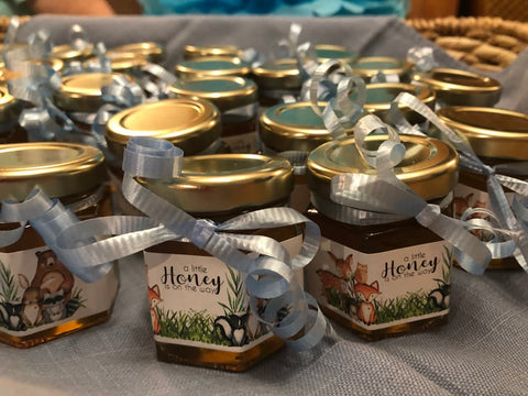Small jars of honey with decorative labels and ribbons on a gray surface