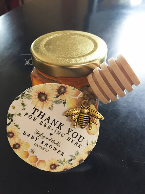 Honey jar with a decorative label and honey dipper on a dark surface