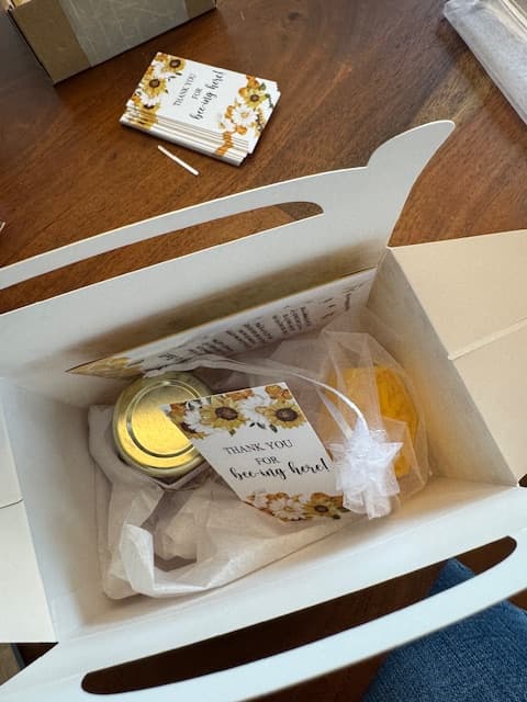 Gift box with a jar, cards, and other items on a wooden surface