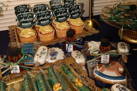 Display of decorated cupcakes, honey bears, and cookies on a table.