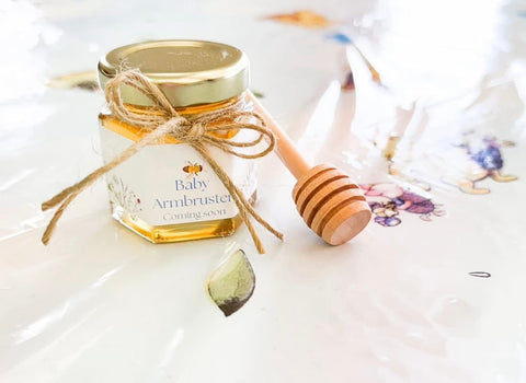 Jar of honey with a wooden dipper on a white surface