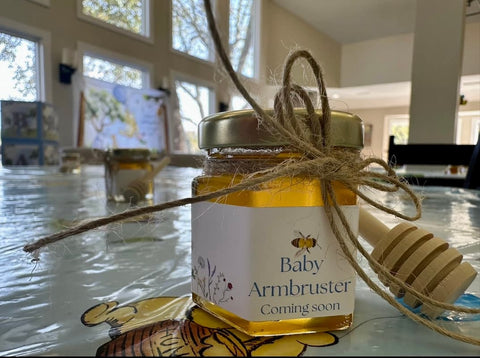 Jar of honey with a baby announcement label on a table