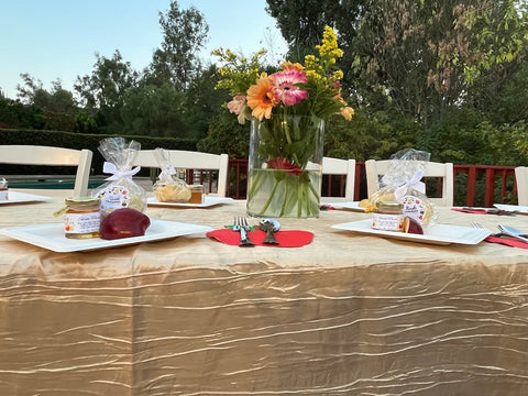 Set table with flowers, food, place settings, and cutlery outdoors