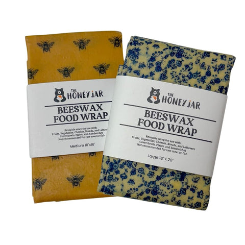 Two beeswax food wraps with bee and floral patterns and labels from The Honey Jar on a white background