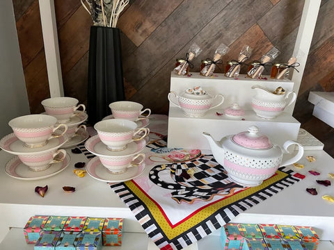 Tea set with pink and white design on a table with decorative elements.