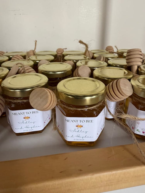 Jars of honey with 'Meant to Bee' label on a wooden surface