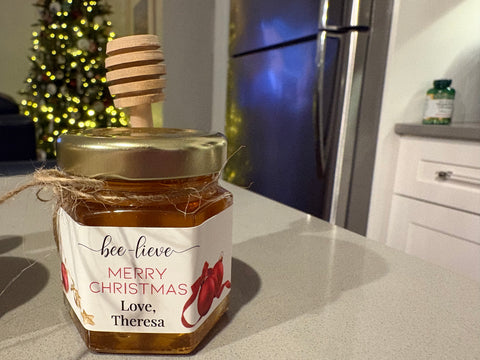 Jar of honey with a decorative label on a kitchen counter, Christmas tree in the background