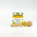Jar of honey with a personalized label, gold thank you charm, and wooden honey dipper on a white background