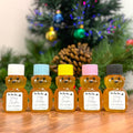 Five bear-shaped honey bottles with colorful lids in front of a decorated Christmas tree.