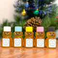 Five bear-shaped honey jars with colorful lids on a wooden surface, Christmas tree in the background.