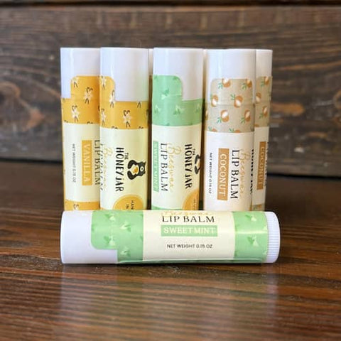 Set of lip balms with visible "The Honey Jar"branding on a wooden surface