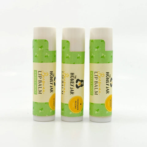 Three lip balms with green and beige packaging on a white background