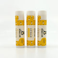 Three lip balms with yellow and white packaging on a white background