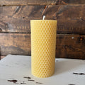 Beeswax candle with honeycomb pattern on a wooden surface