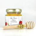 Honey jar with a gold lid and a wooden honey dipper on a white background