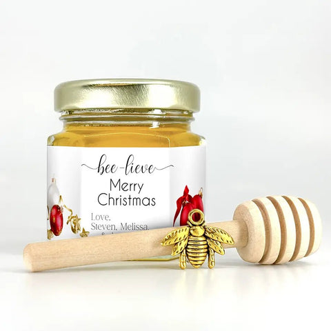 Honey jar with a gold lid and a wooden honey dipper on a white background