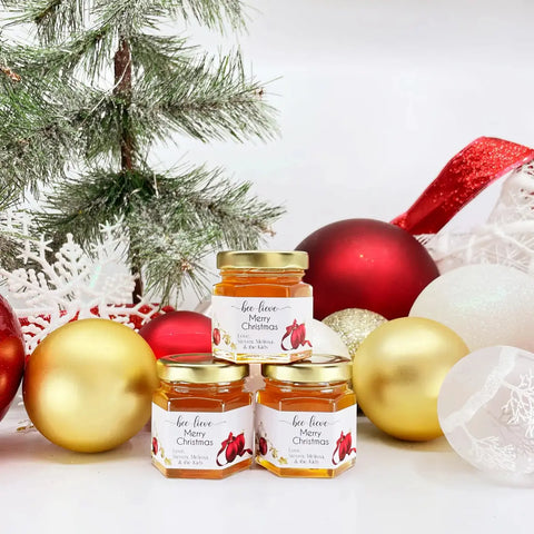 Jars of honey with Christmas decorations on a white background