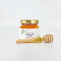 Jar of honey with a personalized label and wooden honey dipper on a white background