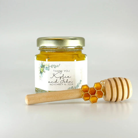 Jar of honey with a personalized label, wooden honey dipper, and honeycomb on a light gray background