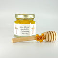 Jar of honey with a personalized label, a honeycomb charm, and wooden honey dipper on a light background